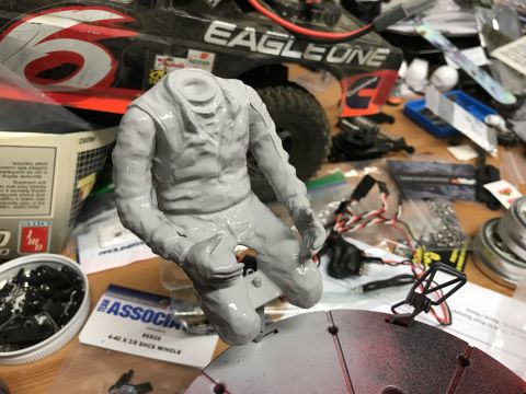 1989 Ford Bronco - A workbench is cluttered with parts for remote control cars, including a headless figure and a partially assembled RC car.