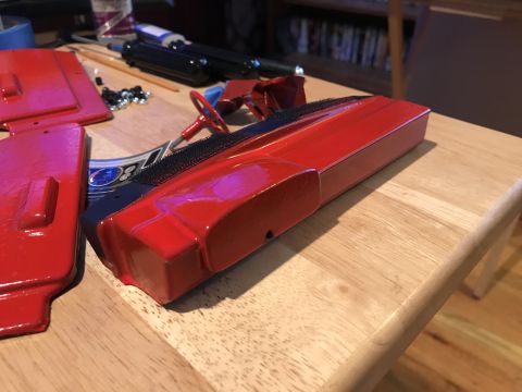 1989 Ford Bronco - Unassembled red toy car parts are laid out on a wooden surface, ready for assembly.
