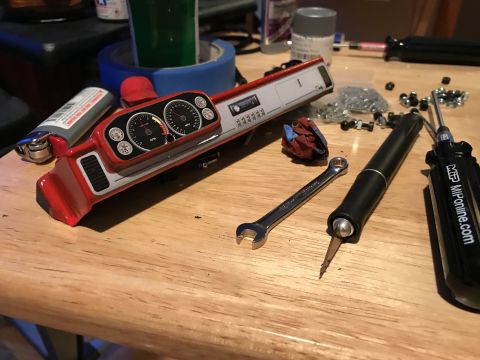 1989 Ford Bronco - Model car dashboard assembly with tools and a lighter on a wooden surface.