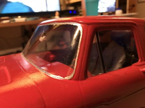 1989 Ford Bronco - Close-up of a red toy truck's cab, showing the windshield and a glimpse of the interior.