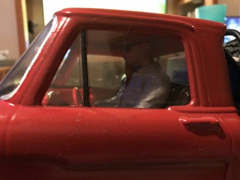 1989 Ford Bronco - The interior of a red toy truck shows a figure in the driver's seat.