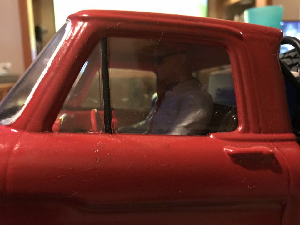 Close-up of a red toy truck's interior with a figure in the driver's seat