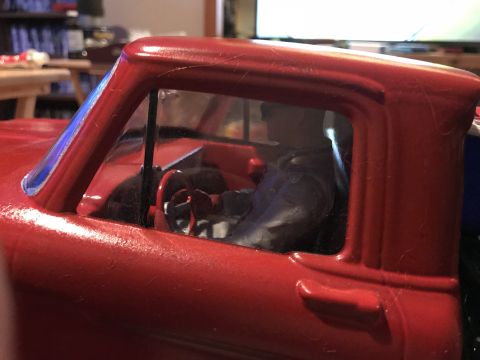 1989 Ford Bronco - Close-up of a red toy truck's interior, showing a figure seated behind the steering wheel.