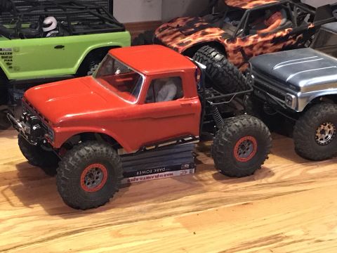 1989 Ford Bronco - Multiple remote control rock crawler trucks are displayed on a wooden surface.