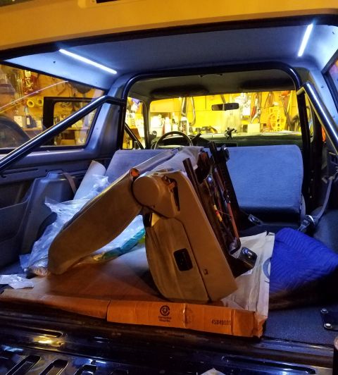 1995 Ford Bronco - The interior of a vehicle shows a removed seat, roll cage, and LED lighting strips installed on the ceiling.