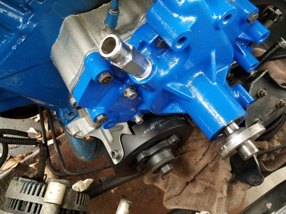 Blue painted engine water pump with timing marks visible on pulley