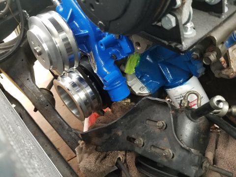 1976 Ford Ranchero - Close-up view of a vehicle's engine water pump assembly, showing the blue-painted pump and shiny metal pulleys.