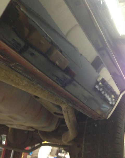 1988 Ford Crown Victoria LTD - The underside of a vehicle reveals exhaust components and a section of the rocker panel.