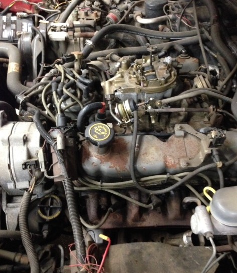 1988 Ford Crown Victoria LTD - Close-up view of a vehicle's engine compartment, showing the carburetor and other engine components.