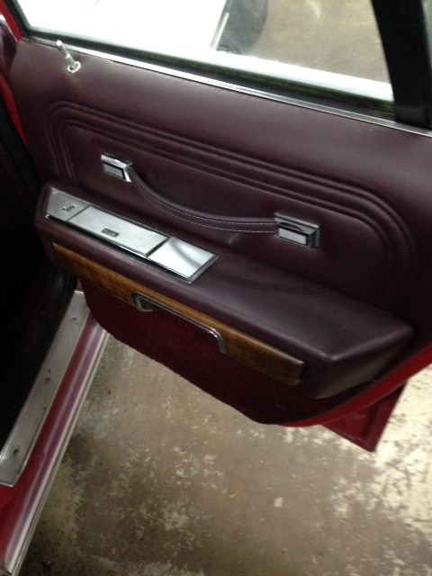 1988 Ford Crown Victoria LTD - The maroon interior door panel of a 1988 Ford Crown Victoria LTD shows wood trim and chrome accents.