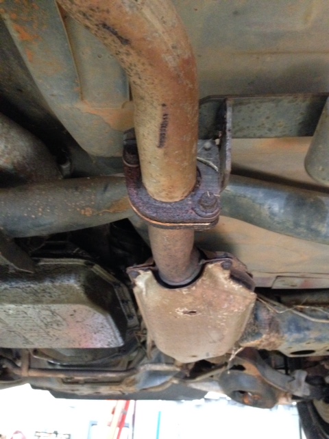 1988 Ford Crown Victoria LTD - The underside of a vehicle shows a rusty exhaust system with a catalytic converter.