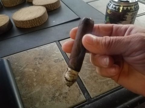 2018 Ford Bronco - A hand holds a cigar over a tiled surface, with a beer can and wooden coasters nearby.