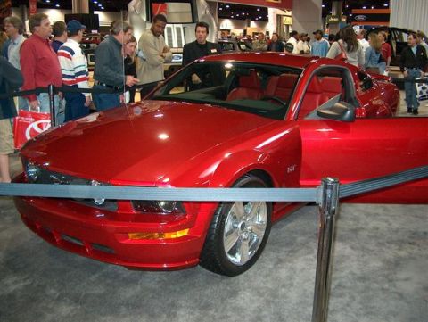 2001 Ford Crown Victoria - A red coupe is displayed with its door open, showing off its red interior at an auto show.