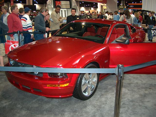 Red coupe with door open, on display at an auto show. Interior is red