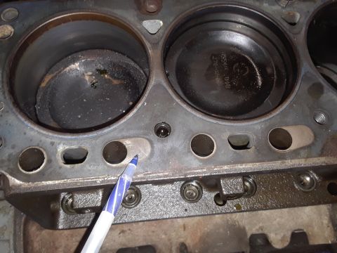 1985 Ford Bronco - Close-up view of an engine block's cylinders and pistons, with a pen indicating a point of interest on the cylinder wall.