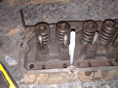 1985 Ford Bronco - Close-up of an engine cylinder head, showing valve springs and pushrods. A tool is inserted into one of the cylinders.