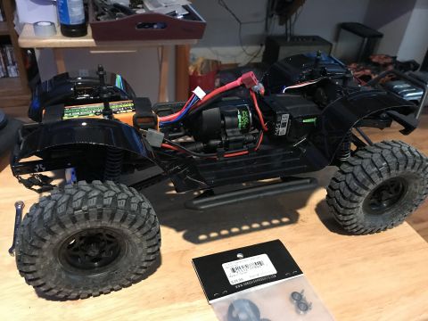 1989 Ford Bronco - An RC car with visible motor, battery, and wiring sits on a wooden surface next to a parts package.