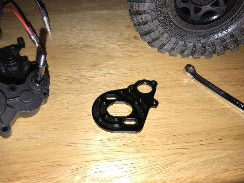 1989 Ford Bronco - Close-up of RC car components including a motor mount, gearbox, and a tire, alongside a wrench.