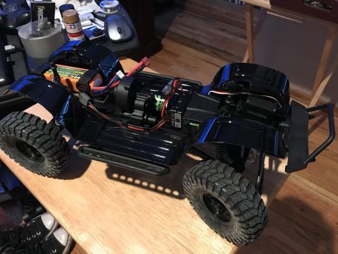 1989 Ford Bronco - Close-up view of a black RC car chassis, showing the battery pack, motor, and electronic components.