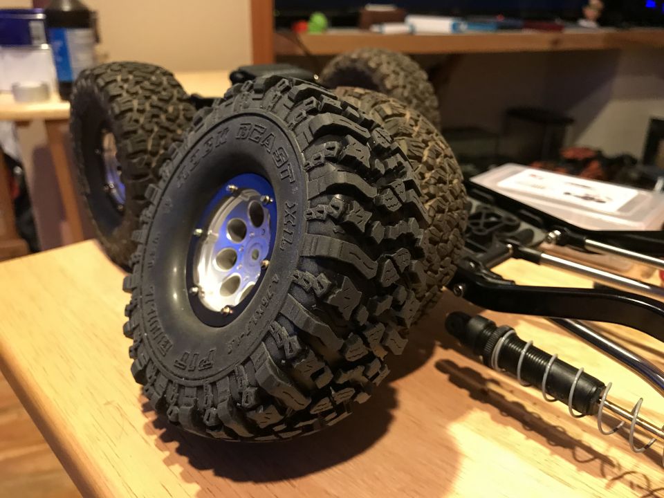 RC car tires with blue-accented rims and black suspension components on a wooden surface