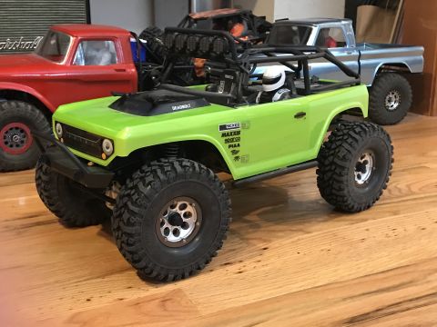 1989 Ford Bronco - This RC rock crawler features a roll cage, a driver figure, and various sponsor decals on its side.