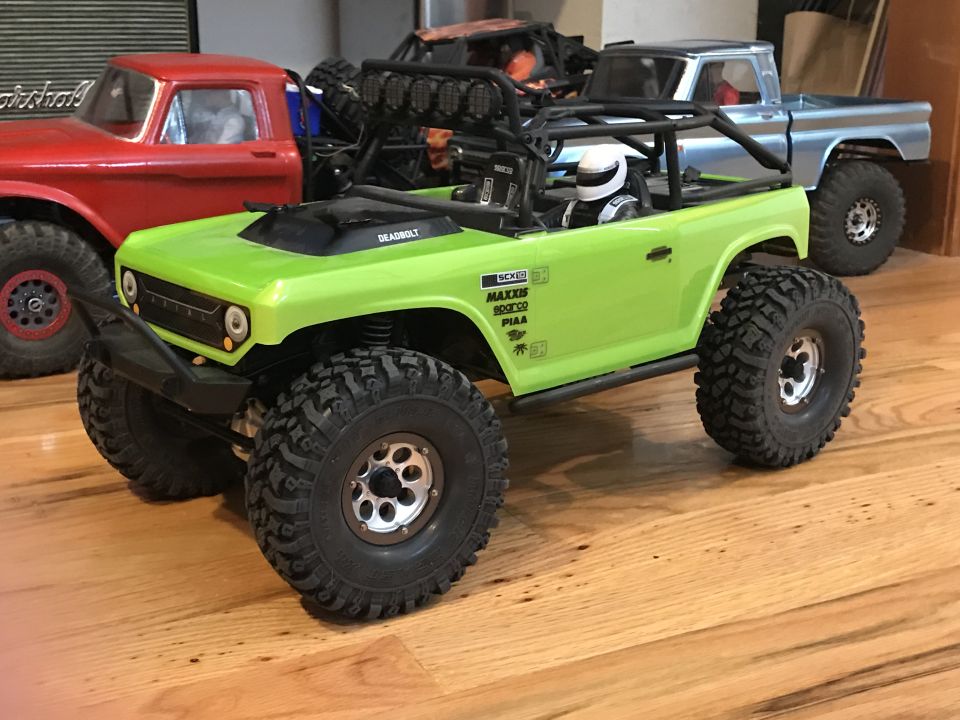 Lime green RC rock crawler with roll cage and driver figure, side view
