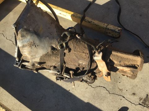 1978 Ford Bronco - Transmission assembly, likely removed from a vehicle, is secured with straps.