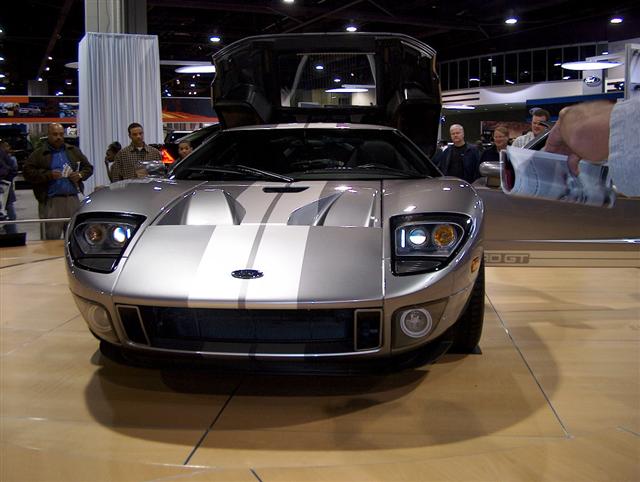 Silver Ford GT sports car, front view, butterfly doors open. Silver stripes on hood and roof