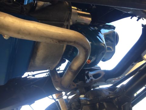 1978 Ford Bronco - Underside view of an engine bay, showing an exhaust pipe and a dark green engine block.