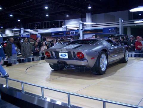 2001 Ford Crown Victoria - A silver Ford GT is showcased at an auto show with spectators in the background.