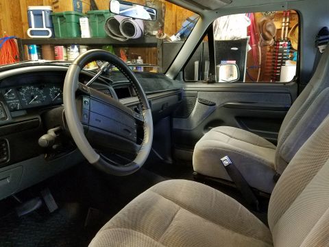1995 Ford Bronco - The interior of a 1995 Ford Bronco, its dashboard, steering wheel, and cloth seats.