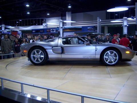 2001 Ford Crown Victoria - A silver Ford GT is displayed at an auto show, with "FORD GT" lettering on its side.