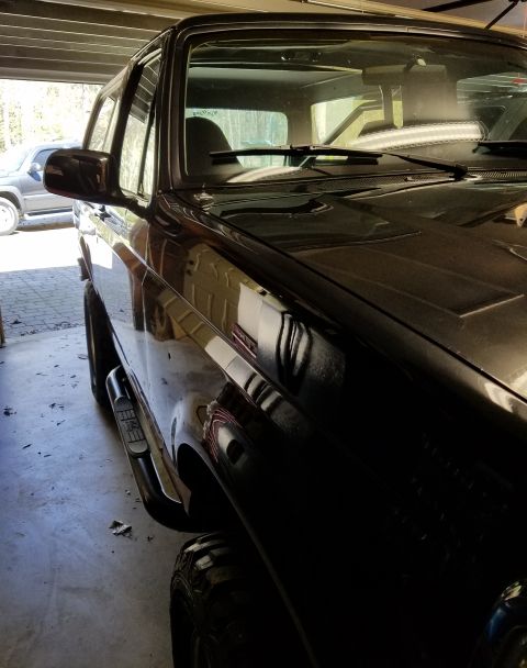 1995 Ford Bronco - A black SUV is parked inside a garage, with another vehicle visible in the background.