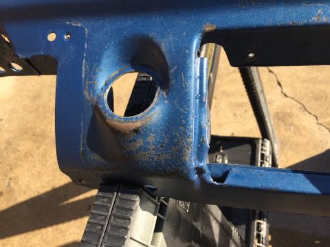 1978 Ford Bronco - A close-up view of a blue metal component a circular opening, likely a part from a vehicle's interior.