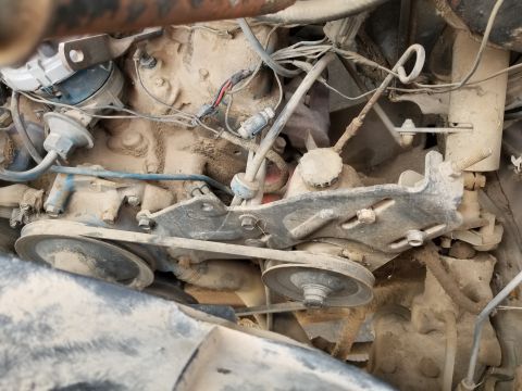 1967 Ford Bronco - The engine bay is covered in dust, with visible belts and pulleys.