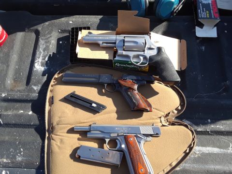 1994 Ford Bronco - A collection of firearms and ammunition are arranged on a mat in the cargo area of a vehicle.