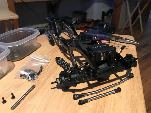 1989 Ford Bronco - The chassis of a remote-controlled car is shown with its components, including a servo and suspension parts.