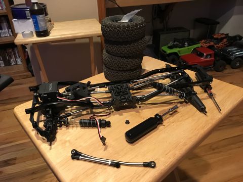 1989 Ford Bronco - RC car chassis and parts laid out on a table, with other RC vehicles in the background.