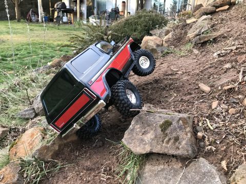 1989 Ford Bronco - An RC rock crawler is shown tipped on its side while navigating a challenging rocky terrain.