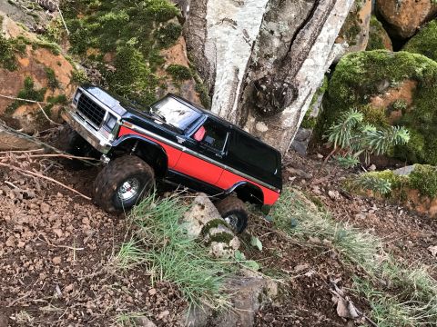 1989 Ford Bronco - This black and red SUV navigates a challenging rocky path, its off-road capabilities.