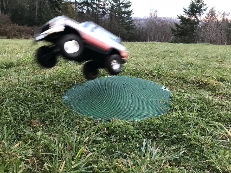 Toy Ford Bronco truck jumping over a green mat on grass
