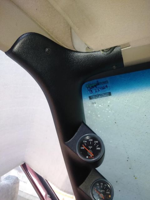 1996 Ford Bronco - A black gauge pod is mounted on the A-pillar of a vehicle, holding two Bosch gauges: one for temperature and one for oil pressure. The inte…
