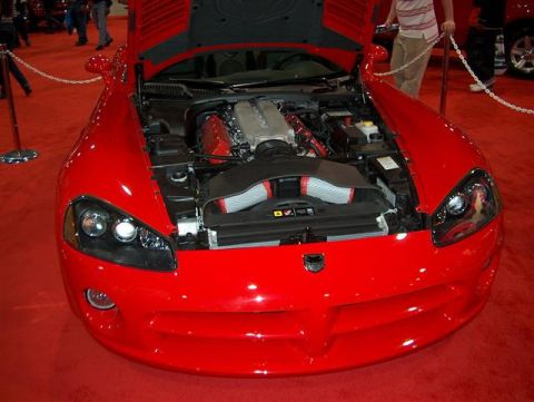 2001 Ford Crown Victoria - A bright red sports car is displayed indoors with its hood raised, revealing the engine compartment.