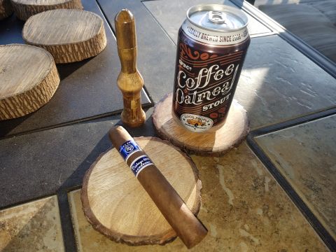 2018 Ford Bronco - A can of "Coffee Oatmeal Stout" from Good People Brewing Company sits on a wooden coaster next to a cigar on another coaster. A wooden ciga…