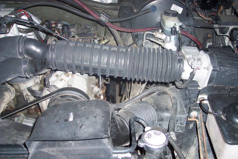 1995 Ford Bronco - The image shows a close-up view of the engine bay of a 1995 Ford Bronco, focusing on the air intake system and engine components. Visible p…