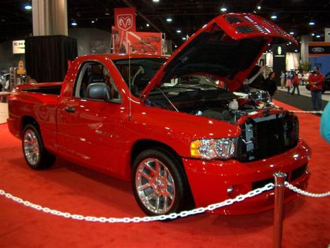 2001 Ford Crown Victoria - A bright red pickup truck is displayed with its hood open at an auto show.