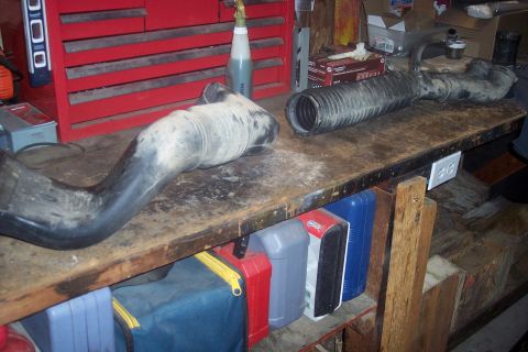 1995 Ford Bronco - Two black rubber intake hoses are laid out on a cluttered workbench. A red tool chest is visible in the background.