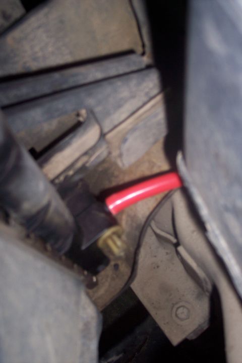 1995 Ford Bronco - A close-up view shows a red hose connected to a black electrical connector, likely part of a vehicle's engine bay.