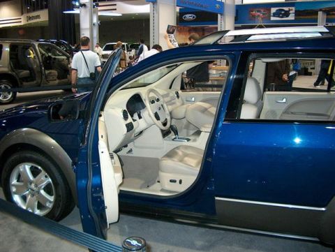 2001 Ford Crown Victoria - Interior view of a blue SUV at an auto show, with another vehicle visible to the left.