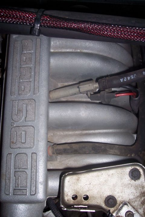1995 Ford Bronco - A close-up view of the intake manifold on a Ford engine. The manifold has the word "5.0" embossed on its side, and various hoses and electr…